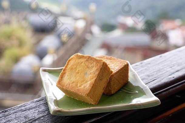 在台湾一家茶馆的木栏杆上，美味的<strong>菠萝</strong>糕点放在一个下午茶的盘子里，背景是美丽的风景，特写。