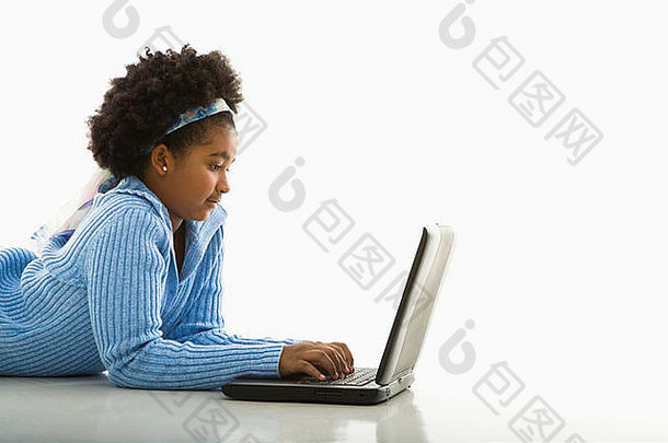 非裔美国女孩使用笔记本电脑躺在地板上的侧视图