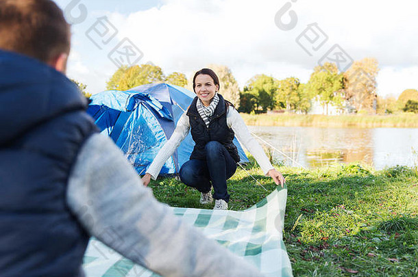 一对幸福的夫妇在营地铺野餐毯