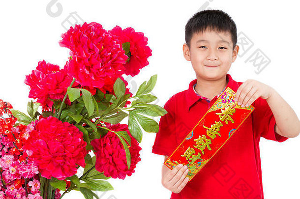 在白色背景上拿着中国新年红对联的亚洲小男孩。对联上的文字在中文里意味着祝你幸福和繁荣。