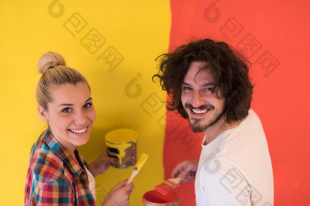 快乐微笑年轻的夫妇绘画室内墙房子