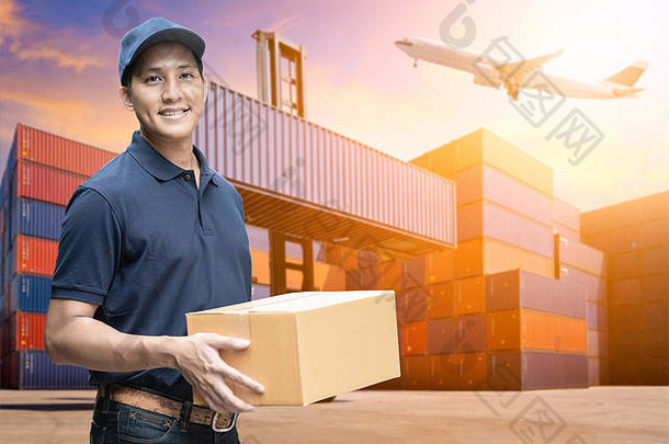 亚洲送货员手持一个纸板箱，具有电子商务和物流概念的物流场背景。