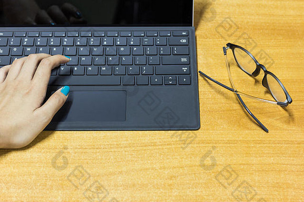 女商人在工作台上手握现代笔记本电脑，工作台配有木制书桌、效果灯和选择焦点。