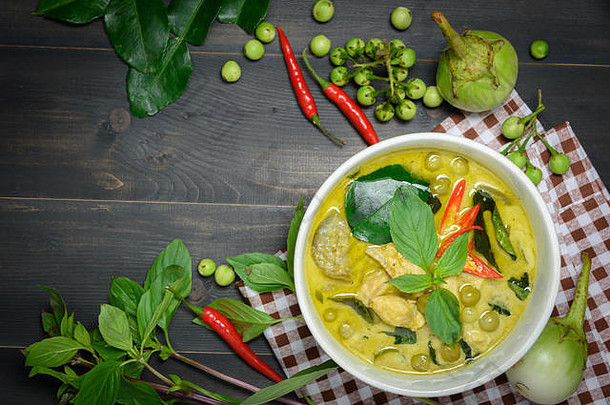 绿色咖喱鸡（Kang Keaw Wan Gai），棕色桌布，木质背景蔬菜俯视图，泰国当地食物