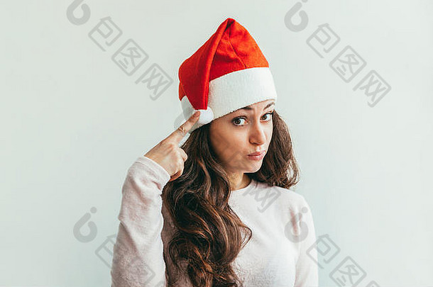 戴着红色圣诞老人帽、留着长发的美丽女孩，被隔离在白色背景上，看上去快乐而兴奋。年轻女子肖像，真实情感。圣诞快乐，新年快乐