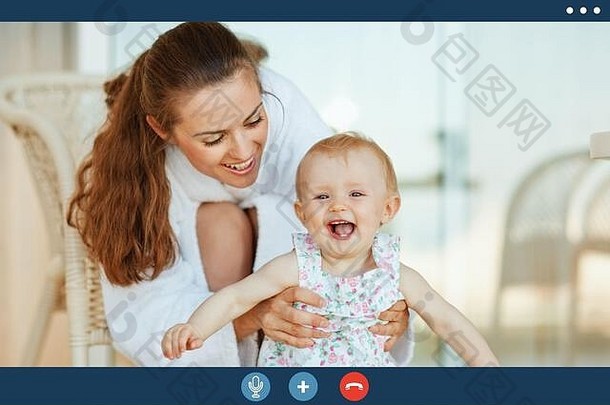 视频调用屏幕年轻的妈妈。浴袍显示可爱的婴儿阳台