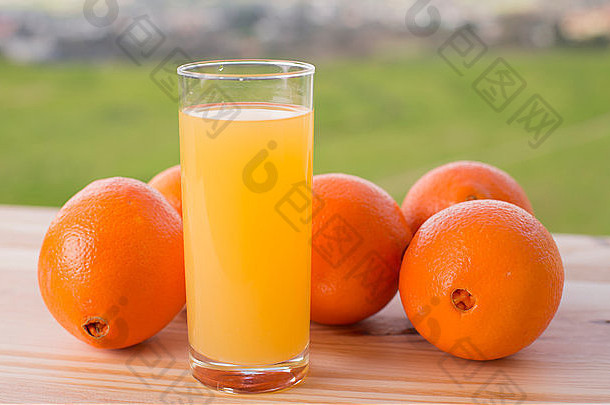 一杯美味的橙汁和橘子放在花园的桌子上