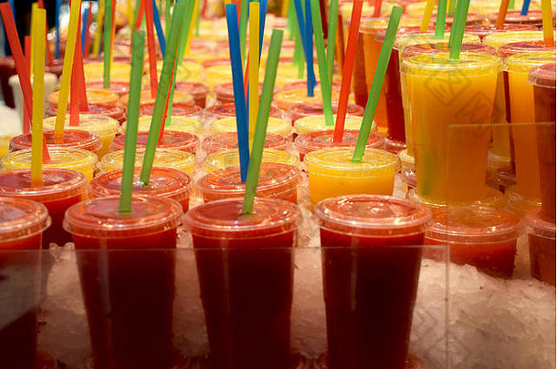 鲜榨橙汁和草莓汁装在塑料杯中，塑料吸管颜色各异