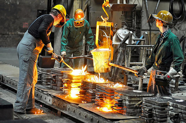 在熔化炉的铸造厂工作的一群工人-在一家工业公司生产铸钢件