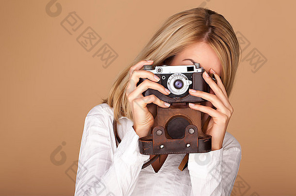 女摄影师在棕色背景上拿着一架老式相机。