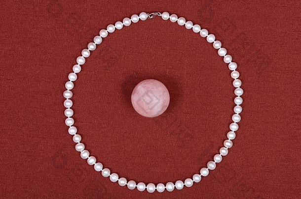 淡水珍珠项链和红色织物背景上的粉红玫瑰石英球