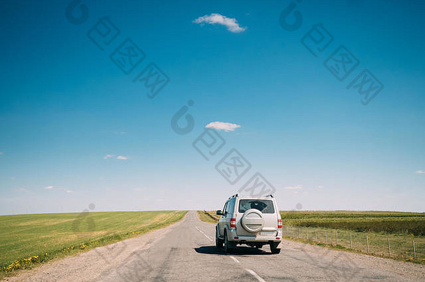 灰色SUV汽车在春夏田野的道路上悠闲地行驶。驾驶和旅行概念。