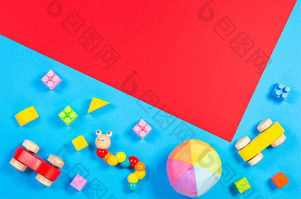 婴儿玩具背景。蓝色和红色背景上的木制汽车、彩色砖块和软玩具