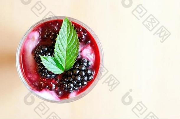 奶油奶酪黑莓甜点玻璃杯顶视图。新鲜的黑莓和薄荷叶放在甜点上