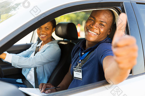 快乐的非洲男驾驶教练坐在一辆车上，学习驾驶的人伸出大拇指