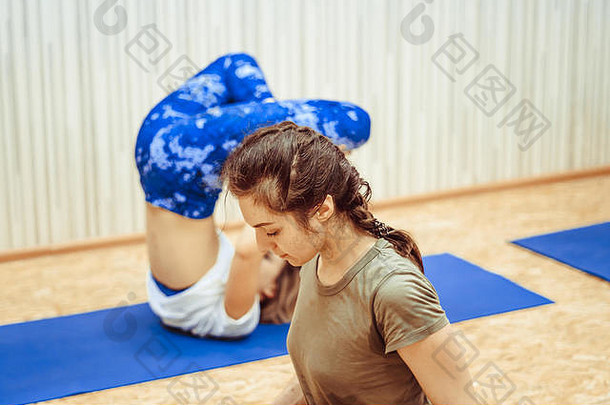 穿着运动服的漂亮女孩正在体育<strong>馆</strong>的<strong>瑜伽</strong>垫上做<strong>瑜伽</strong>