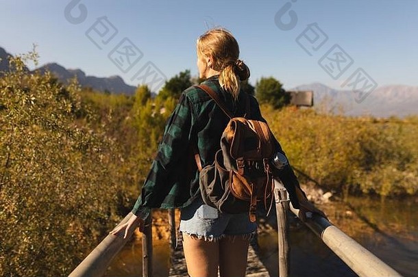 背着背包走在桥上的女人的后视图