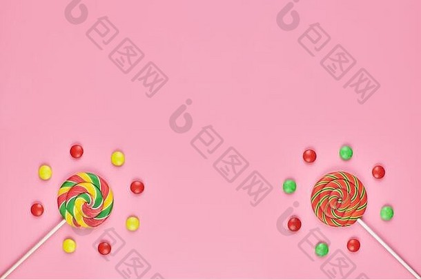 粉红色背景上的甜棒棒糖和糖果，空间。儿时喜欢五颜六色的甜食