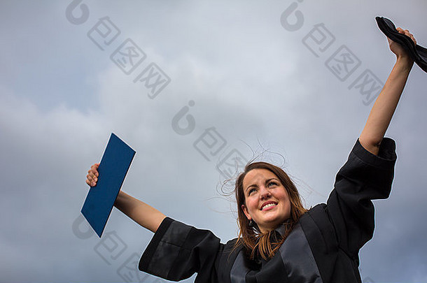 美丽的年轻女子欢庆她的毕业典礼——张开双臂，拿着毕业证书，品味她的成功（c