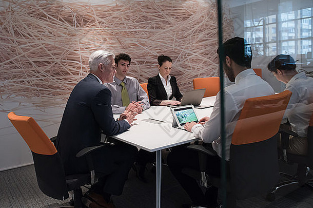 商务人士小组在会议上集思广益，商人在笔记本电脑和平板电脑上展示想法和项目