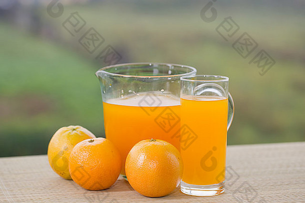 一杯美味的橙汁和橘子放在花园的桌子上