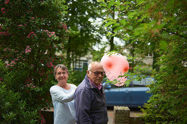 爷爷奶奶前面花园持有大心形状的气球