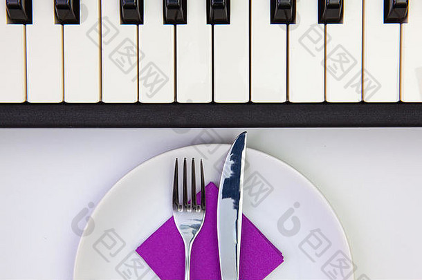 品味的交响乐。白色木桌上的白色盘子和钢琴键。俯视图。平层图像。