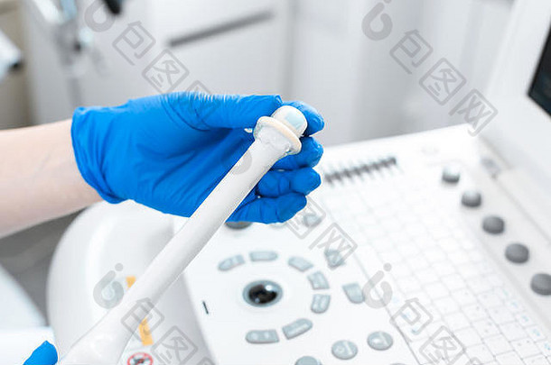 妇科医生在超声波传感器上放置避孕套，检查患者骨盆的内部器官。