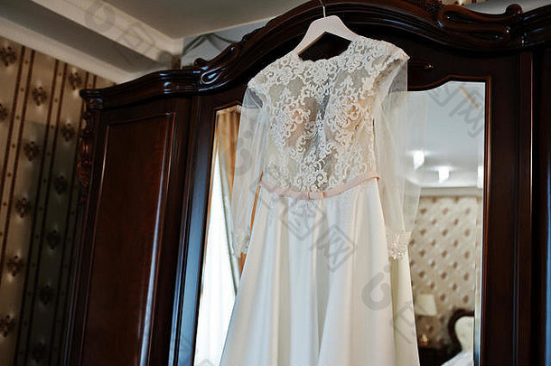 新娘房木制衣橱的衣架上挂着令人惊叹的婚纱。