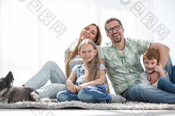 快乐的一家人坐在新客厅的地毯上