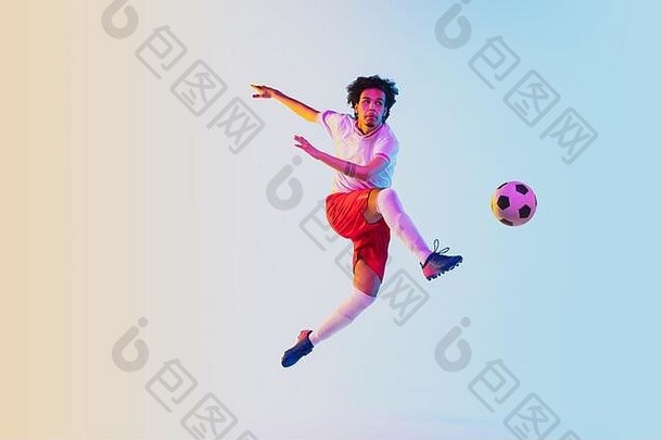在跳跃中踢球，在奔跑中。在霓虹灯的梯度背景上的足球或足球运动员-运动、动作、活动。运动、竞赛、胜利、行动、动作、克服的概念。空间。