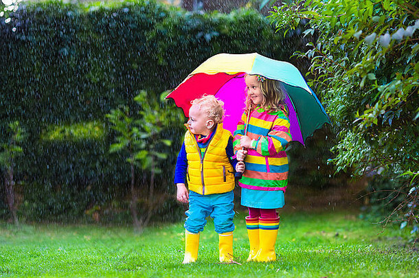 女孩男孩色彩斑斓的伞玩雨孩子们玩户外多雨的天气秋天