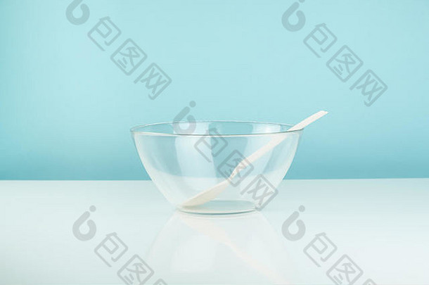 桌子上的空玻璃碗和勺子。饥饿或饮食概念：白色和蓝色背景的干净透明餐具