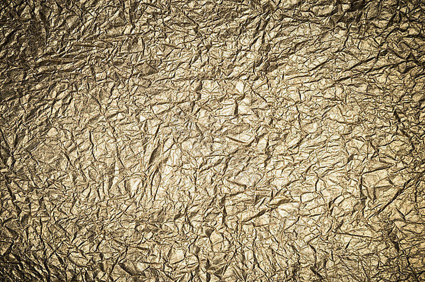 褶皱纹理金属金格伦格背景的特写镜头，带有暗晕阴影