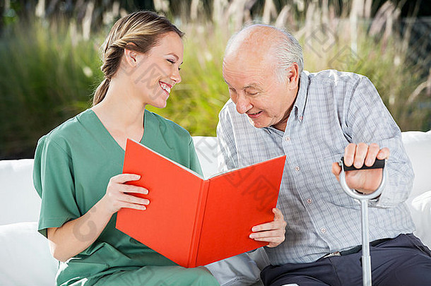 微笑的女护士一边看书一边看着老人