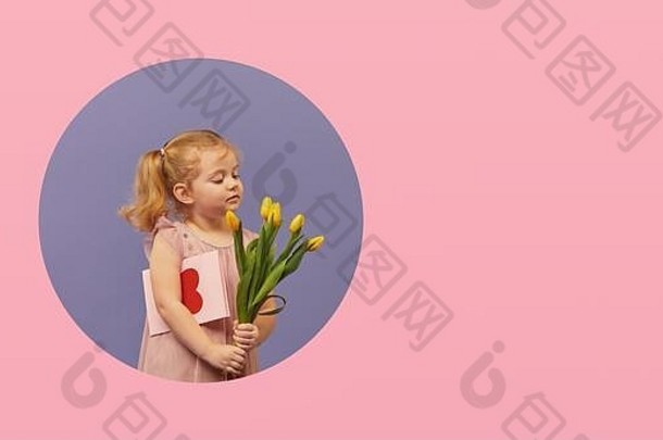 可爱的微笑着的孩子，带着春天的花束，在墙上的圆洞里放着灰色的卡片。一个蹒跚学步的小女孩，手里拿着黄色郁金香作为礼物送给孩子们