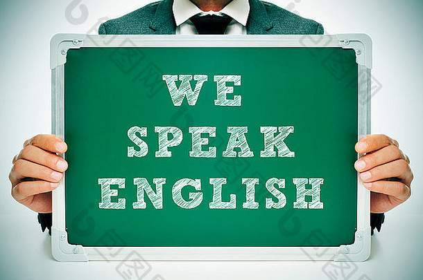 一个穿着西装的男人拿着一块黑板，上面写着“我们说英语”