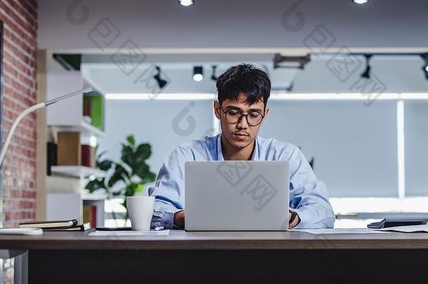 亚洲商人在办公室办公桌上用笔记本电脑和文件工作。数字工作流程在线商务生活方式概念