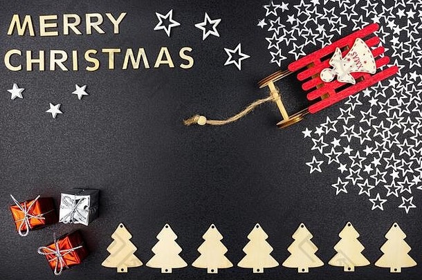 铭文“圣诞快乐”是由木制字母组成的，从上方平躺在黑色背景上。站在银色雪橇上的红色雪橇