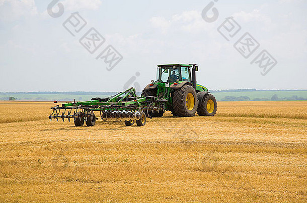 拖拉机与耕耘机连接在一起收割成熟的麦田