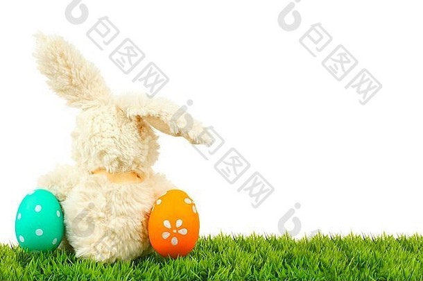 草地上的玩具复活节兔子，五颜六色的彩蛋形成一个角落的边界