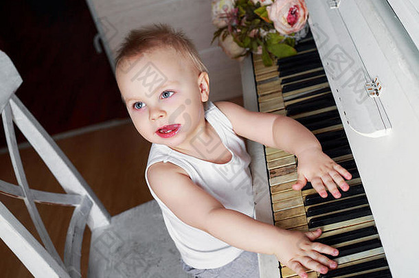 一岁的小男孩正在弹一架旧钢琴