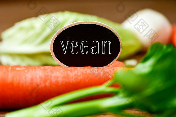 一个黑色招牌的特写，在一堆不同的生蔬菜上放着“素食主义者”，如胡<strong>萝卜</strong>、防风草、胡<strong>萝卜</strong>