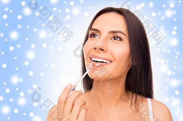 年轻的女人化妆口红雪概念