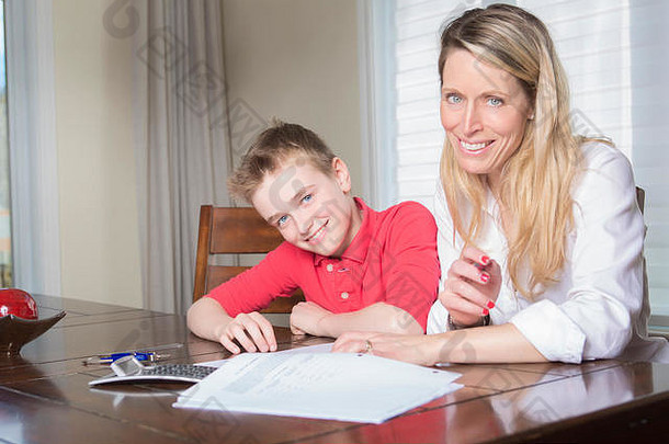母亲在餐桌旁帮助她的小儿子做家庭作业