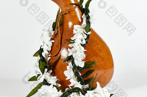 白色花朵夏威夷花环，绿色扭曲的钛叶花环放在夏威夷Ipu打击乐器上，用于呼啦圈