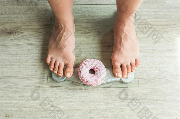 饮食概念特写镜头女人的脚重规模甜甜圈概念糖果不健康的垃圾食物肥胖