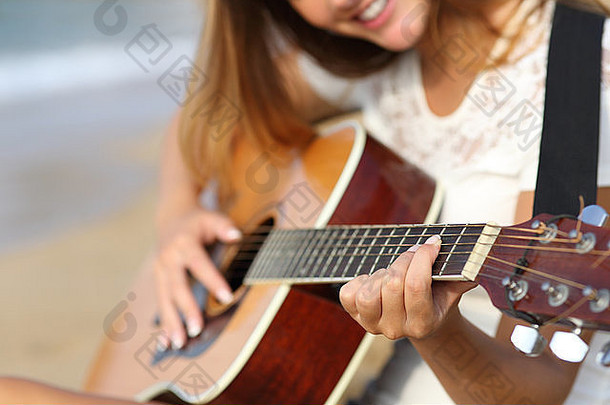 一个夏天阳光明媚的日子里，一个女人在海滩上弹吉他的特写镜头