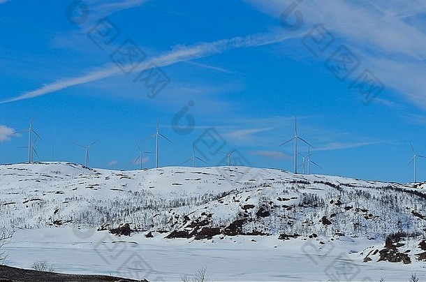 阳光明媚的冬天，雪山山顶上的风车公园