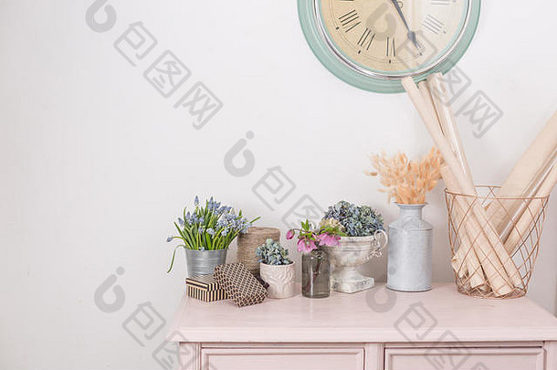 春天的心情。复古室内装饰。粉色粉彩壁橱。在木桌上晾干鲜花。白色墙上的大钟。拷贝空间